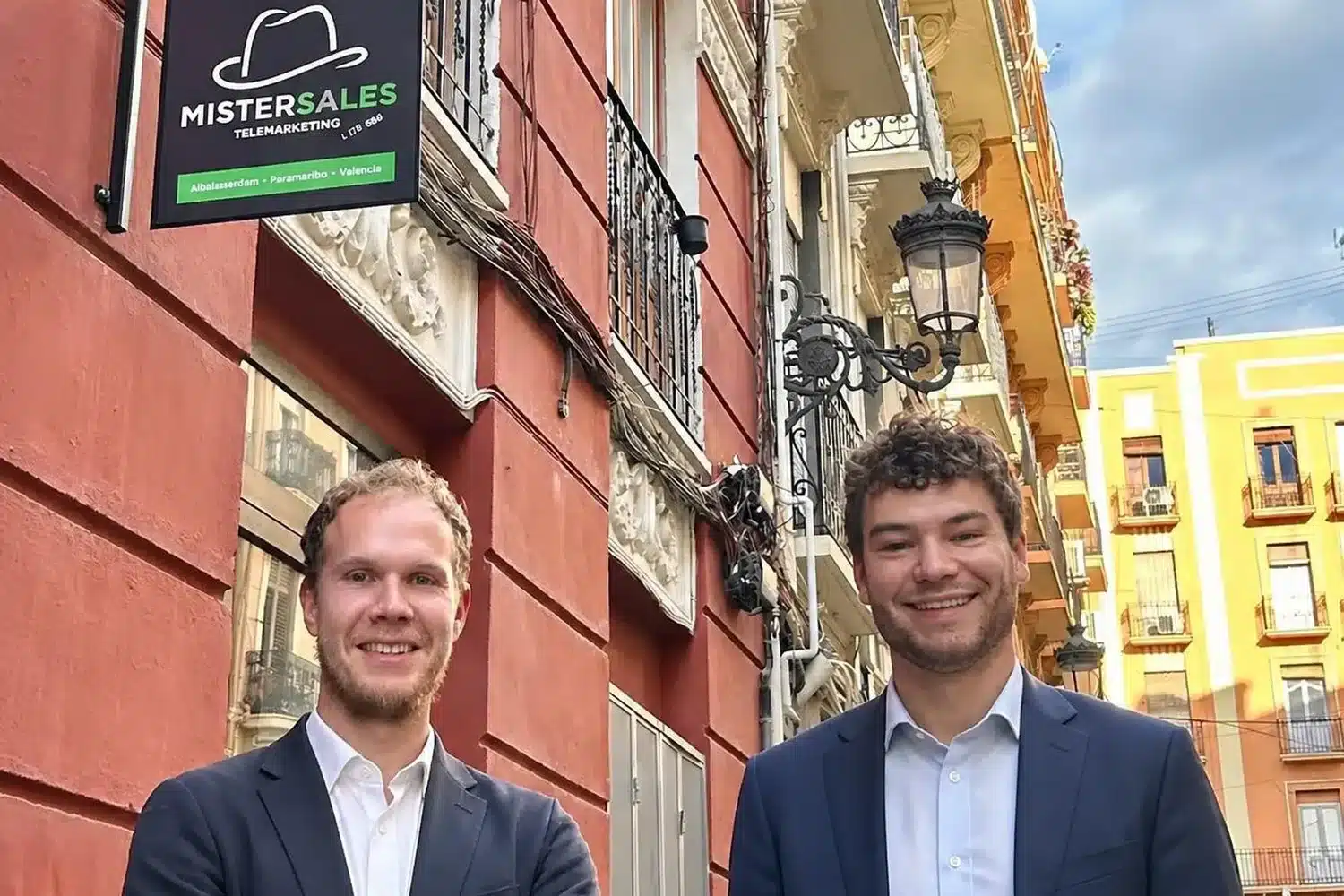 Twee collega's voor het kantoor in Valencia met een mooi uithangbord waarop het logo van MisterSales staat